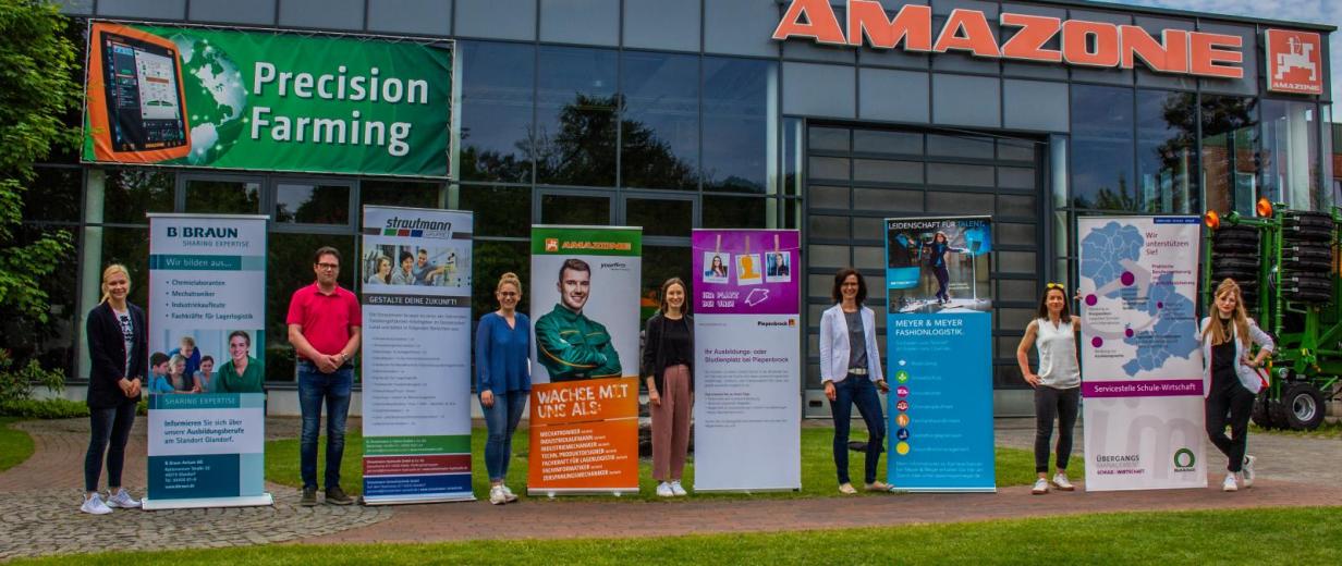7 Personen mit Werbeplakaten vor dem Unternehmen Amazone