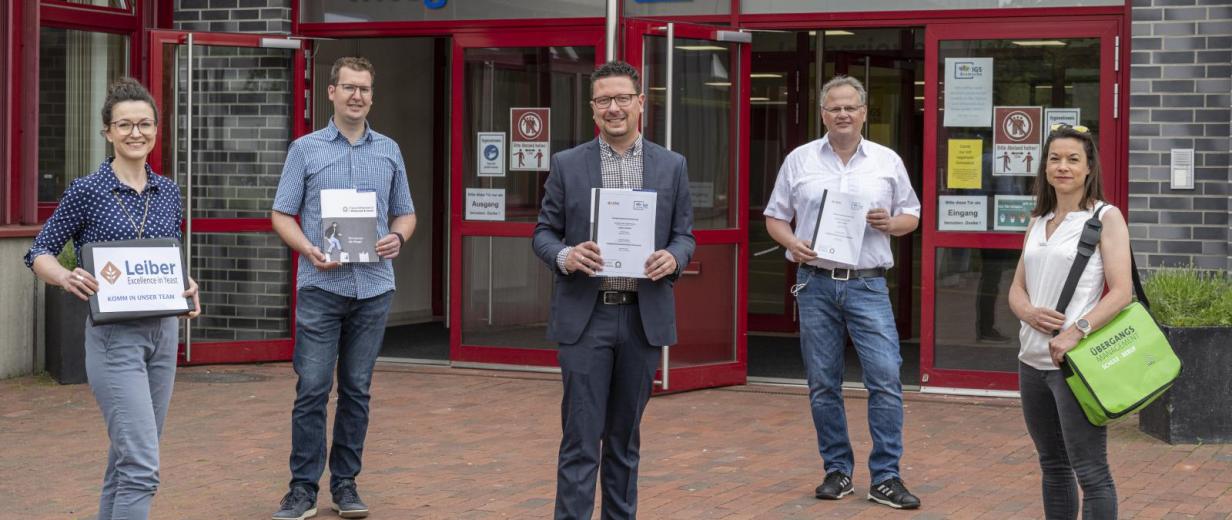 5 Personen vor dem Eingang einer Schule