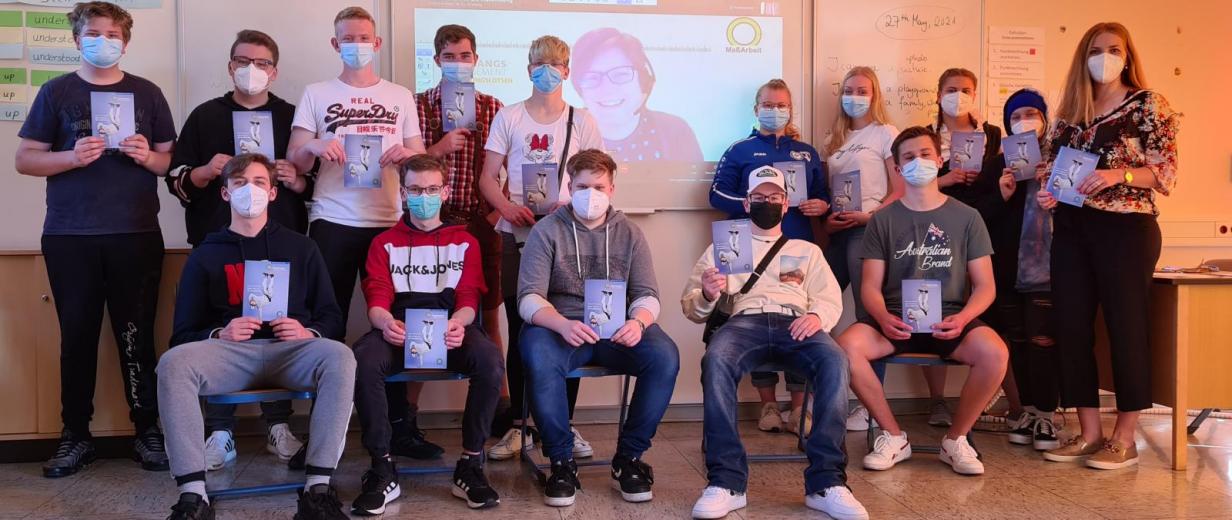 Gruppenfoto einer Schulklasse mit Lehrerin. Alle tragen Corona Mundschutz.