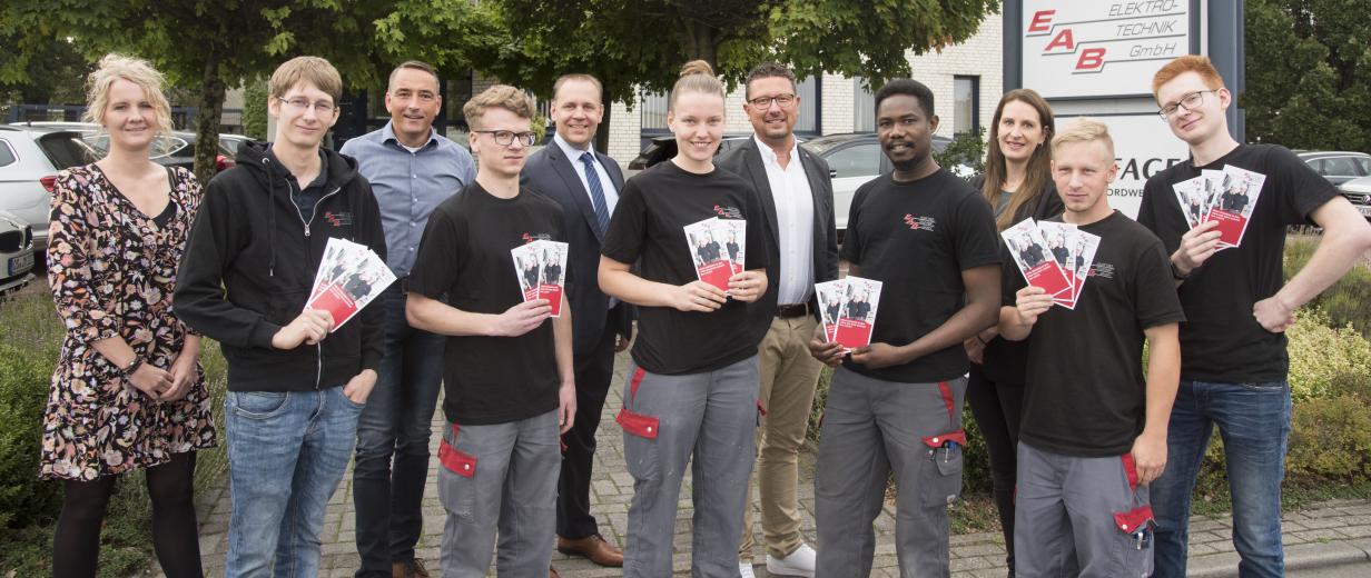 Eine Personengruppe mit Flyern in der Hand steht vor einem Gebäude.