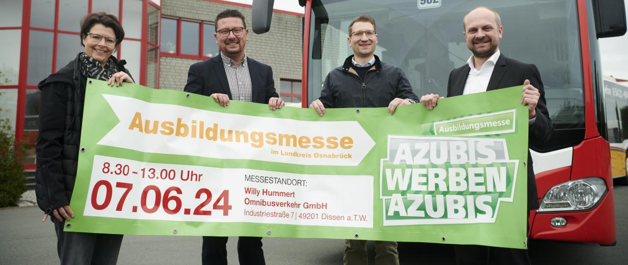 Vier Personen mit einem Banner in den Händen stehen vor einem Linienbus.