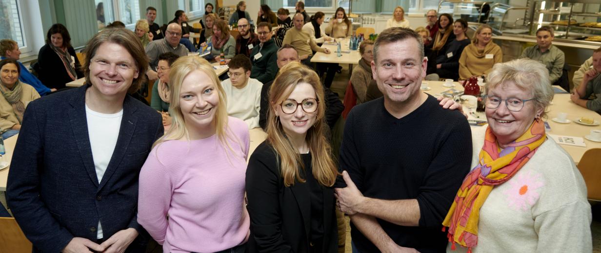 Netzwerktreffen KI, Digitalisierung Fünf Personen stehen in einer Reihe im Hintergrund ein Sitzungssaal.