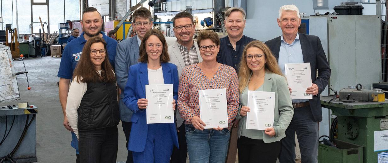 MaßArbeit, Renzenbrink Metallbau Neun Personen stehen in einer Werkhalle.