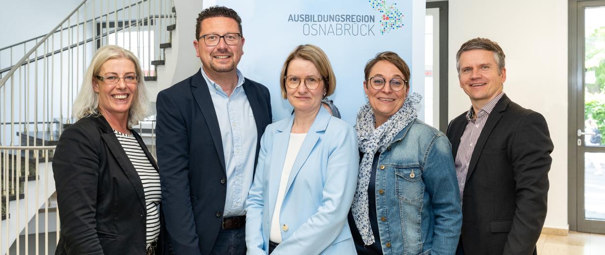 Ausbildungsregion Verein Internetportal Fünf Personen stehen vor einem Rollup-Poster in einem Treppenhaus.