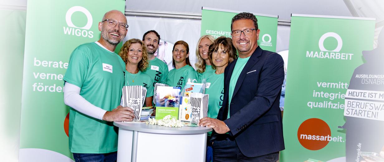 WIGOS und MaßArbeit beim Tag der Niedersachsen Personengruppe steht an einem Messestand mit Rollups im Hintergrund.