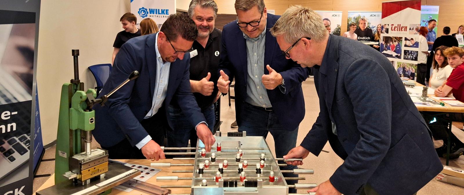 Vier Personen stehen an einem Kickertisch.