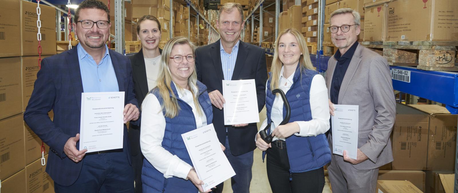 Sechs Personen stehen in einem Hochregallager.