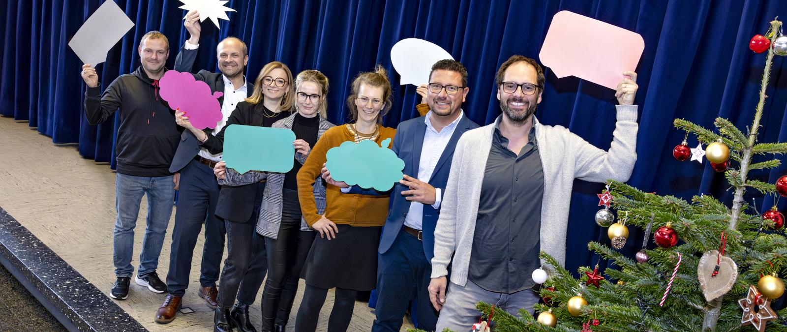 Eine Personengruppe steht auf einer Bühne.