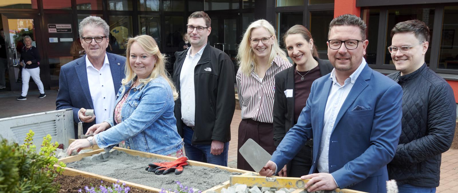 Sieben Personen stehen vor einem Gebäude.