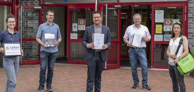 5 Personen vor dem Eingang einer Schule