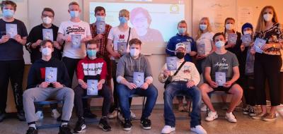 Gruppenfoto einer Schulklasse mit Lehrerin. Alle tragen Corona Mundschutz.