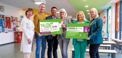 Sechs Personen halten zwei Schilder in die Kamera.