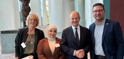Vier Personen stehen im Foyer eines Gebäudes.