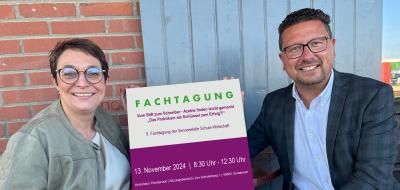Zwei Personen halten ein Schild in die Kamera.