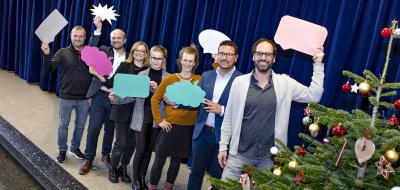 Eine Personengruppe steht auf einer Bühne.