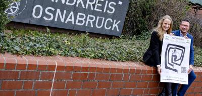 Landrätin und Maßarbeit-Vorstand Hellmers auf einer Mauer sitzend