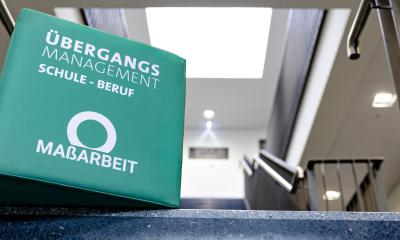 Ein großer Würfel mit MaßArbeit Logo liegt auf einer Treppe.