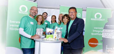 Personengruppe steht an einem Messestand mit Rollups im Hintergrund.