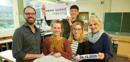 Fünf Personen stehen in einem Klassenraum.