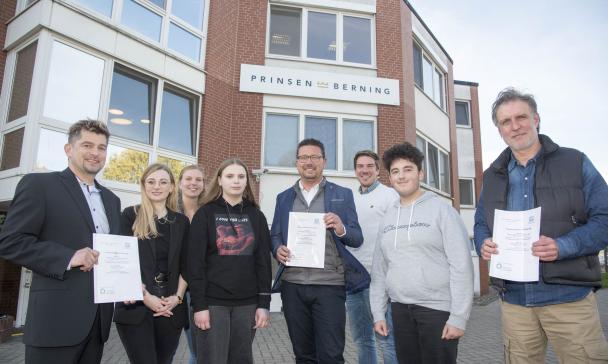 Eine Gruppe von Personen steht vor Firmengebäude