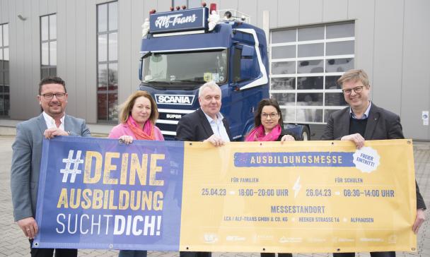 5 Personen in Reihe vor Plakat