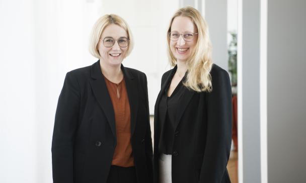 Zwei Personen stehen nebeneinander und schauen in die Kamera.
