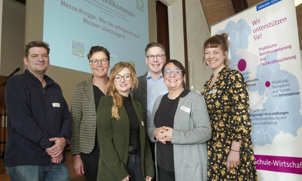 6 Personen vor Plakat