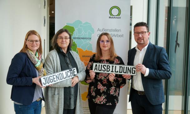 Vier Personen stehen vor einem Roll Up Poster.