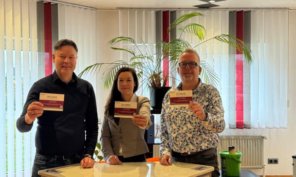 3 Personen vor Tisch stehend