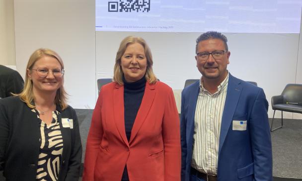 3 Personen vor Plakatwand