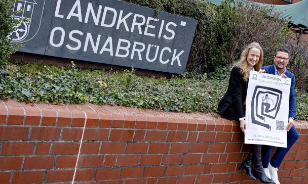 Landrätin und Maßarbeit-Vorstand Hellmers auf einer Mauer sitzend
