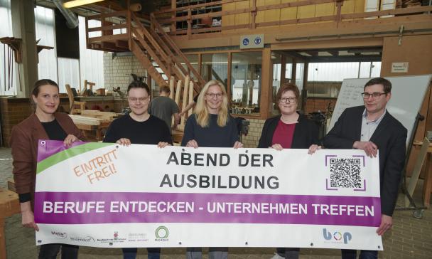 Fünf Personen stehen in einer Werkhalle