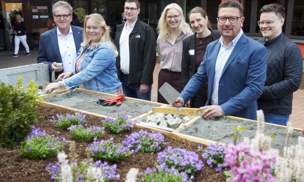 Sieben Personen stehen vor einem Gebäude.